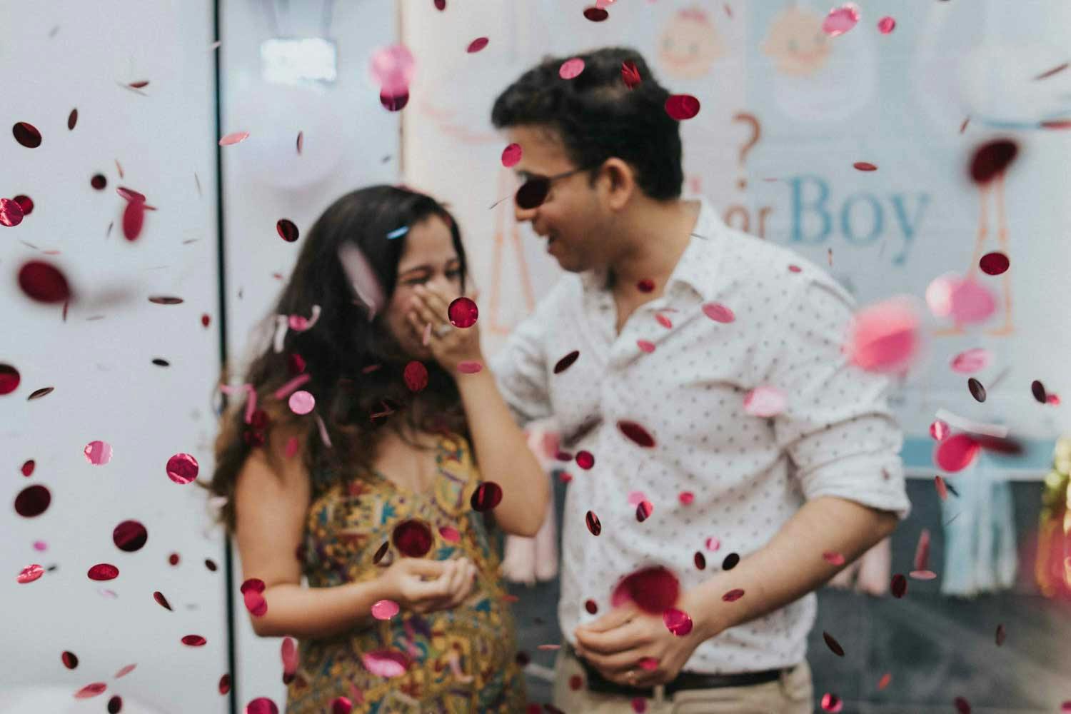 pregnant lady at gender reveal crying in joy with pink confetti flying photography