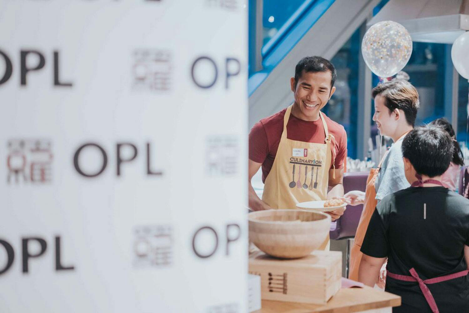 guy smiling behind corporate banner while learning how to bake during a corporate event in Singapore