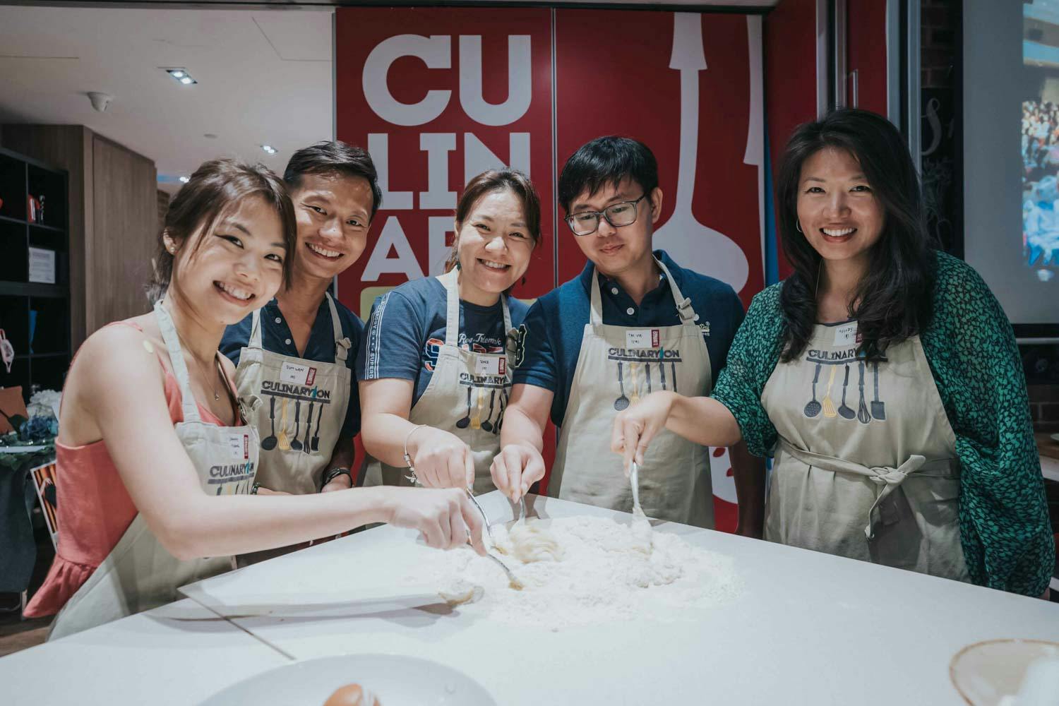 a group of attendees learning how to bake at a corporate event held at a culinary school in singapore