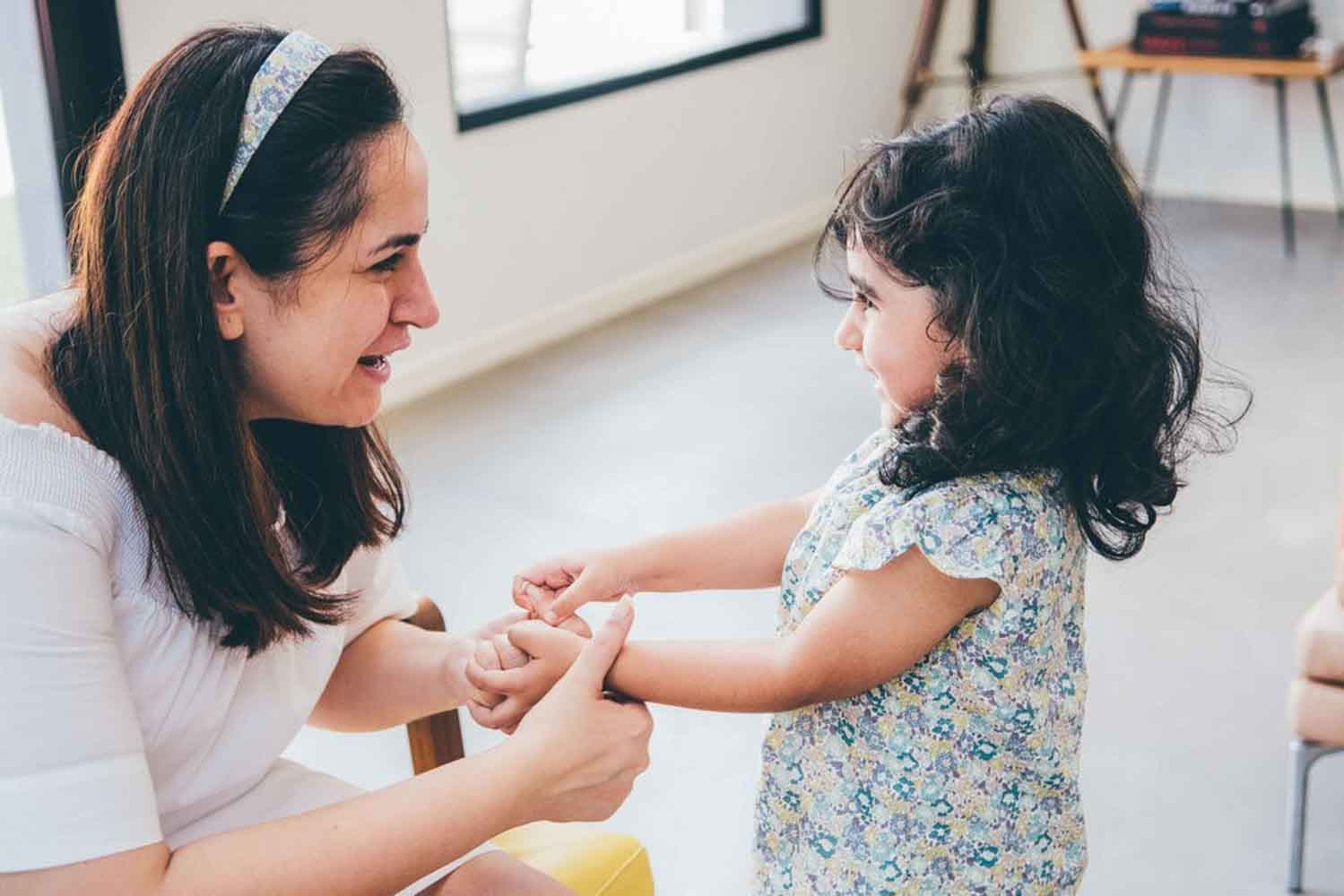 mother holding her daughter's hands and talking to her playfully