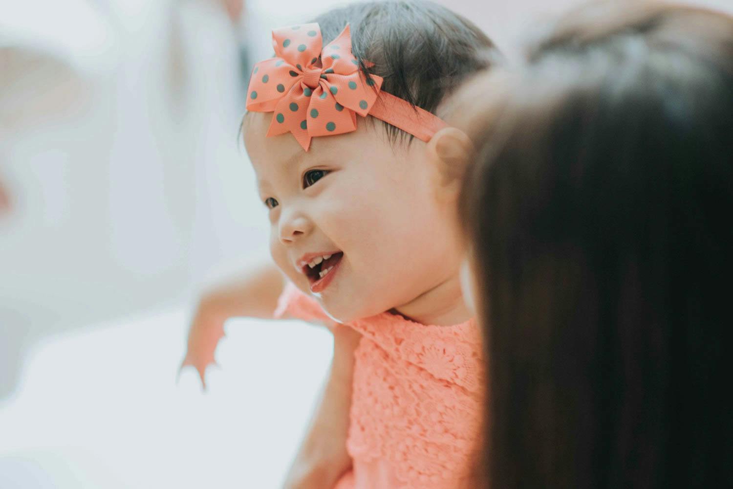 1 year old birthday girl smiling as she plays with her mother during her birthday party