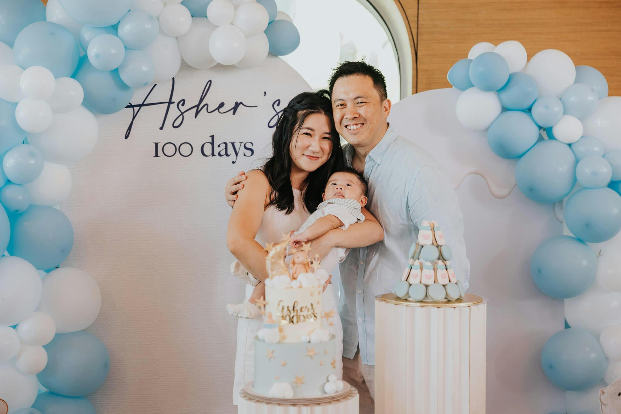 young mom and dad hugging daughter for her 100 day baby birthday party celebration
