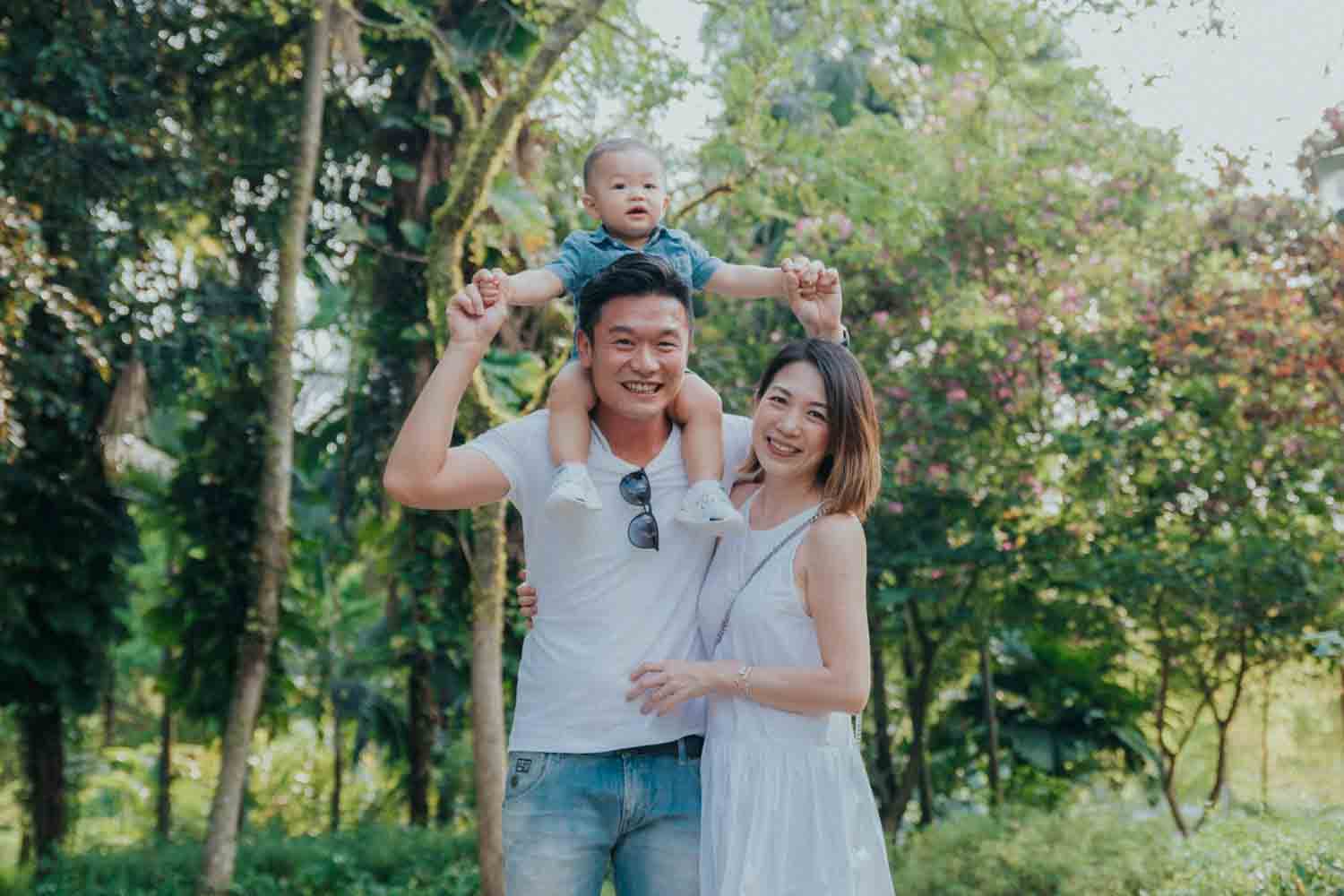 father and mother playing with child as they take a group photo by professional photographer in singapore