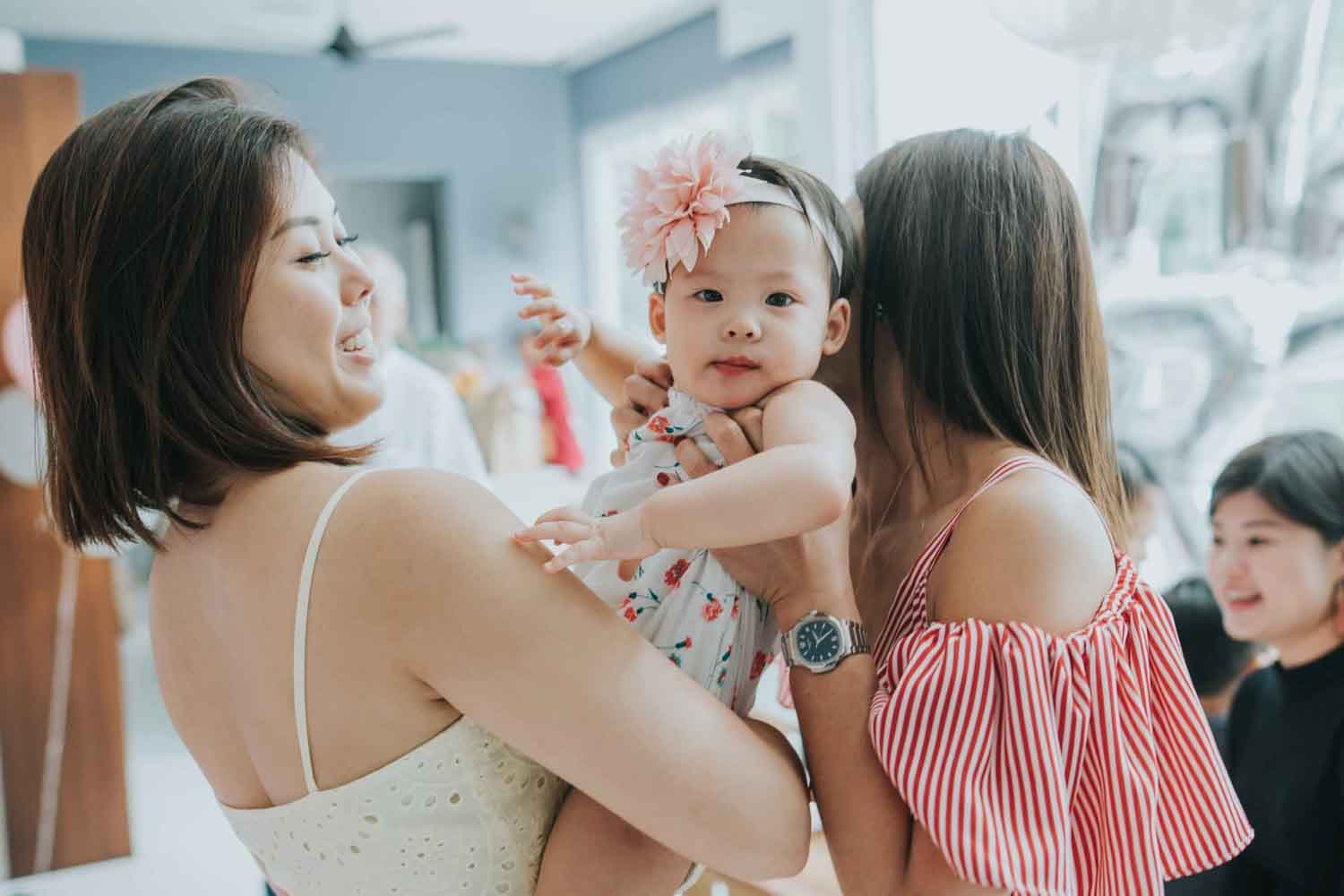 1 year old birthday girl smiling as she plays with her mother during her birthday party