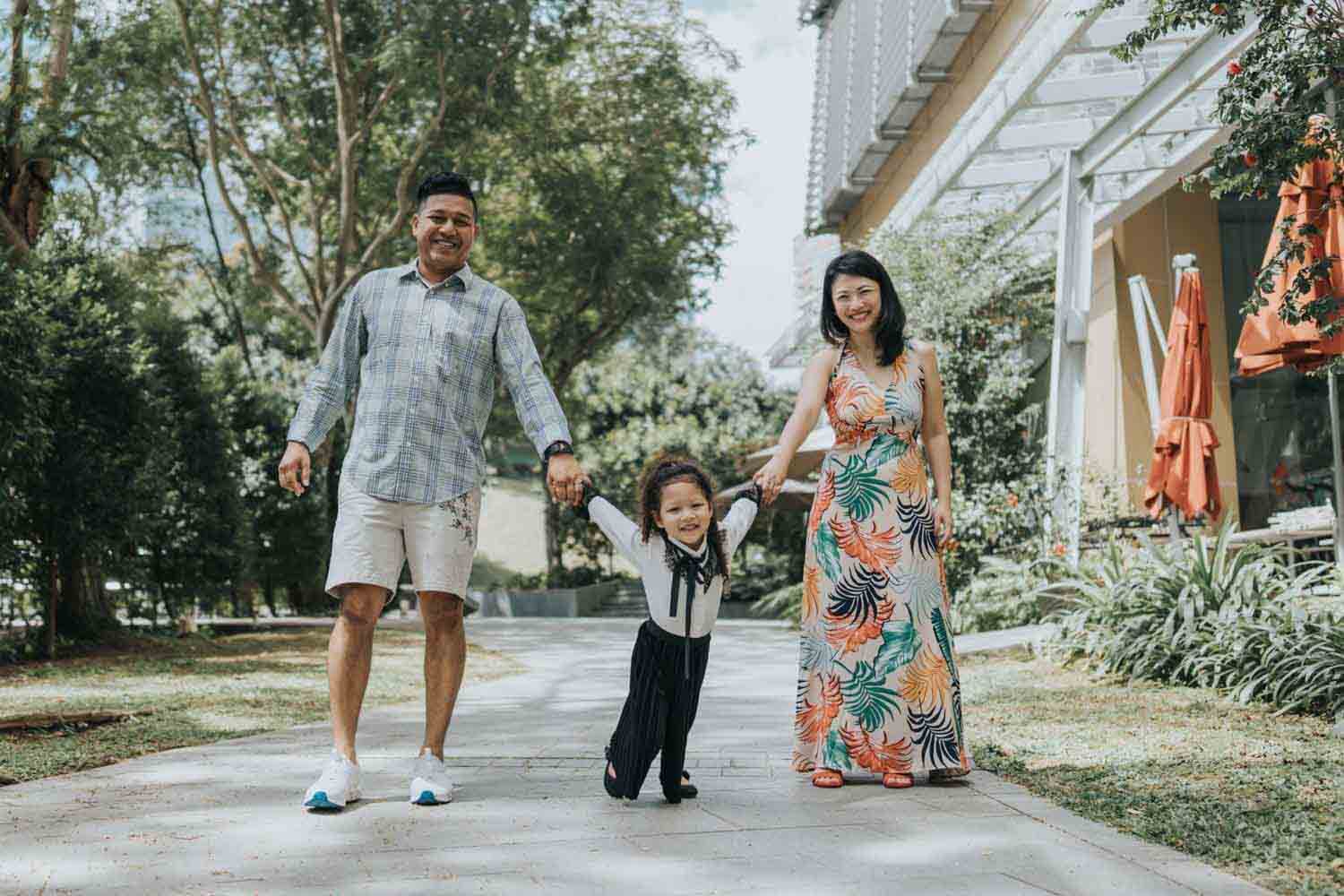 both parents holding hands of their daughter during family photography outdoor shoot in Singapore