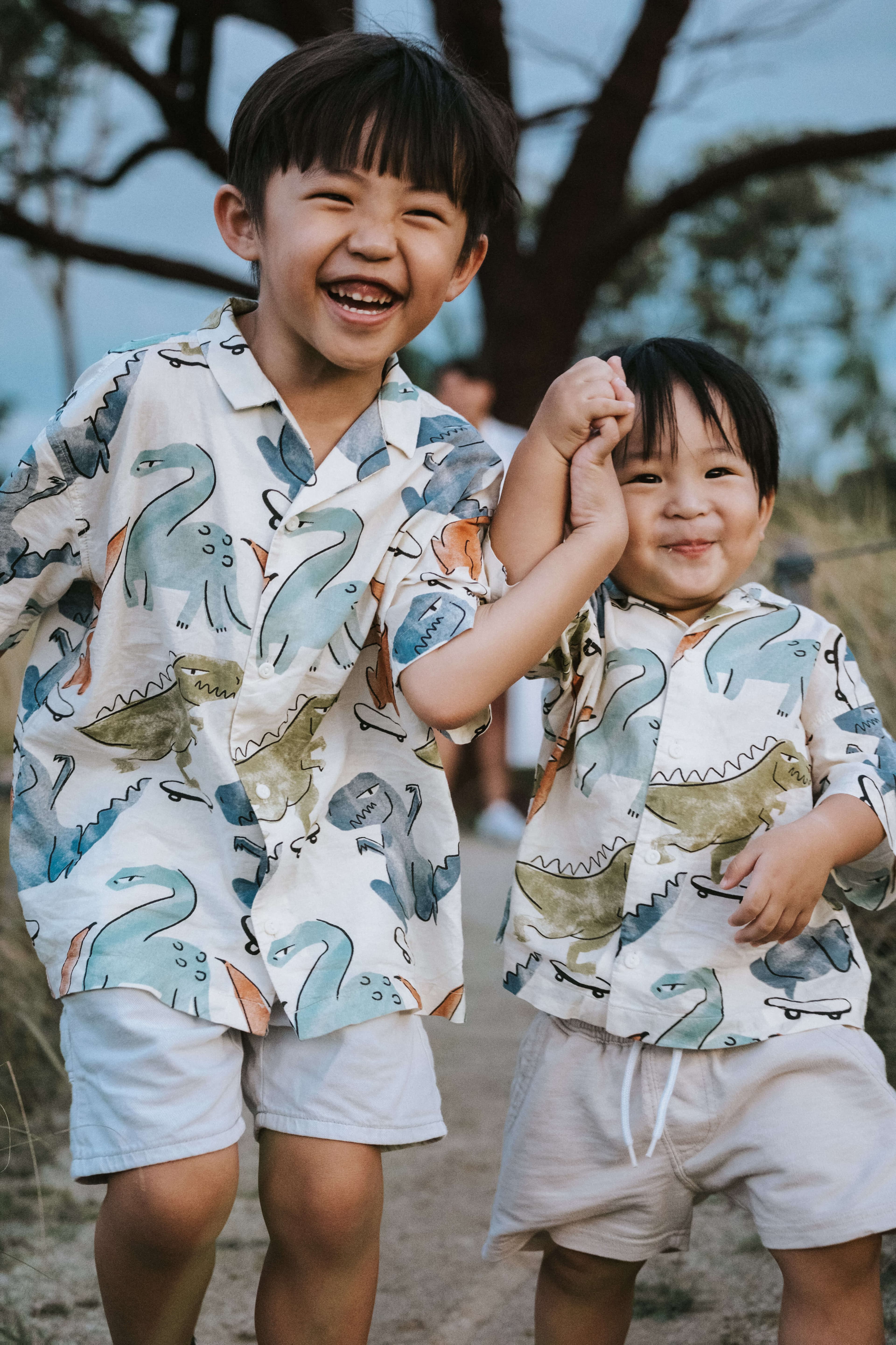 older brother holding younger brother's hand and running while smiling